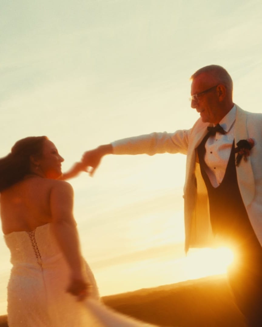 Gareth twirling Kristie on the hill at Mount Macedon Winery as the sun sets behind them, a still from their teaser film