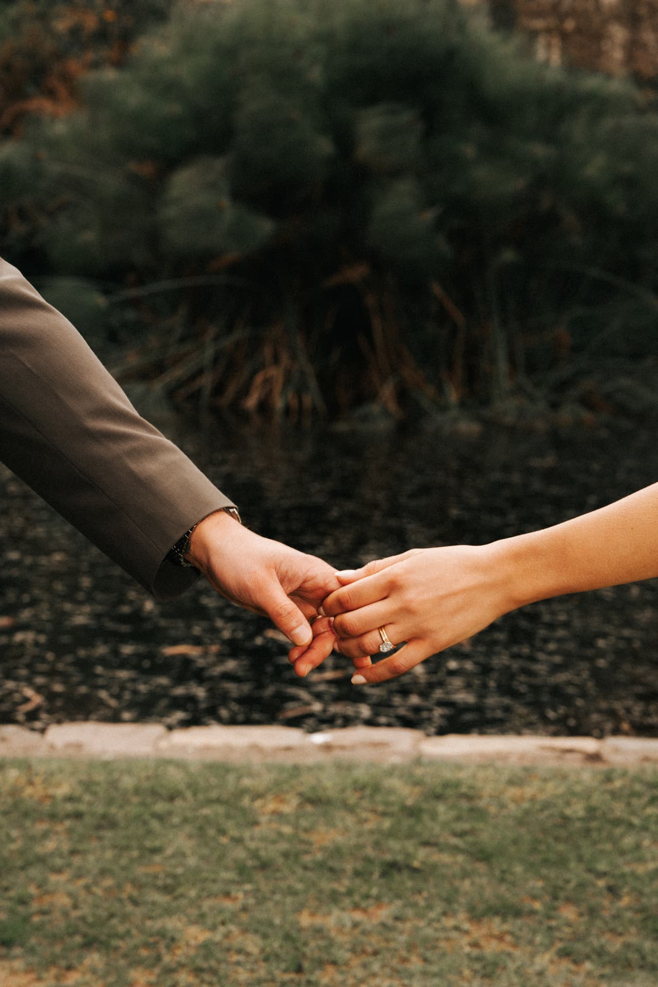 Close up of two hands reaching for each other above a lawn