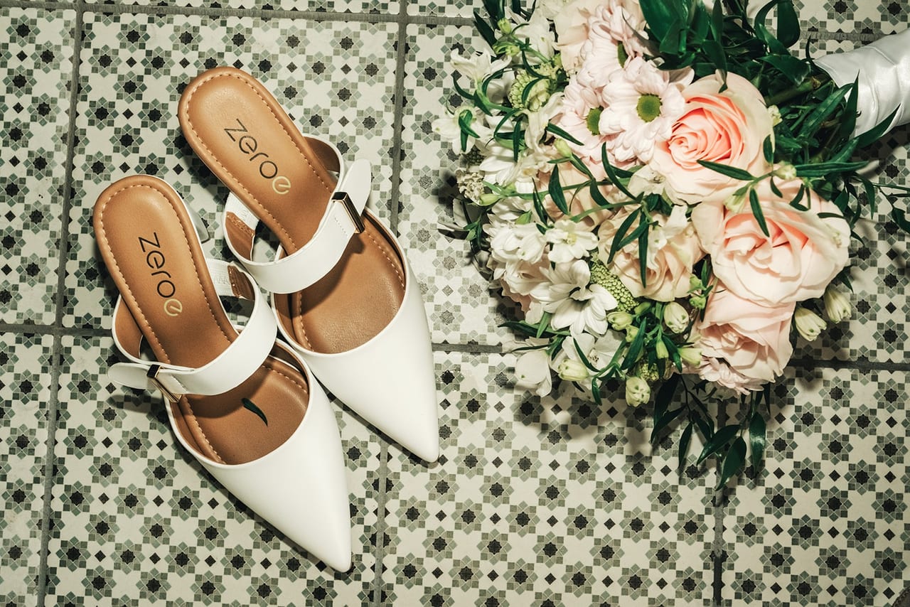 White wedding shoes and a bouquet of roses on patterned floor tiles