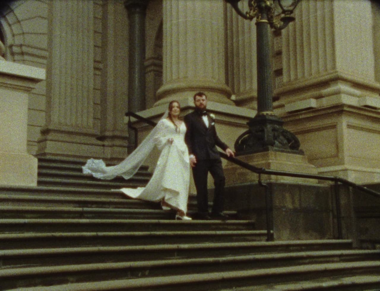 Bianca's veil catching the wind as they come down the steps of Parliament House