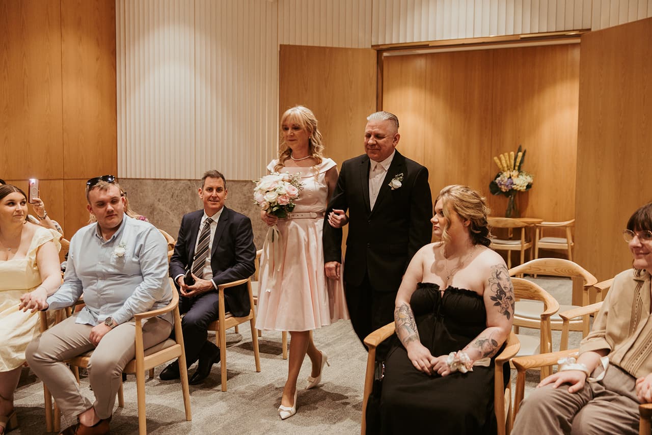 Terrie and Jon walking in between their seated guests in the marriage room
