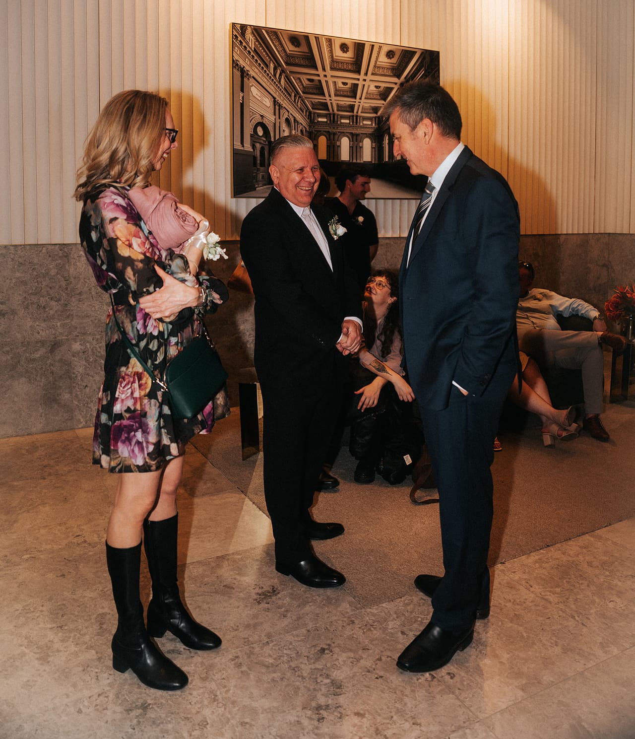 Jon greeting a guest in the registry foyer, a large framed photograph of a grand hall on the fluted white wall