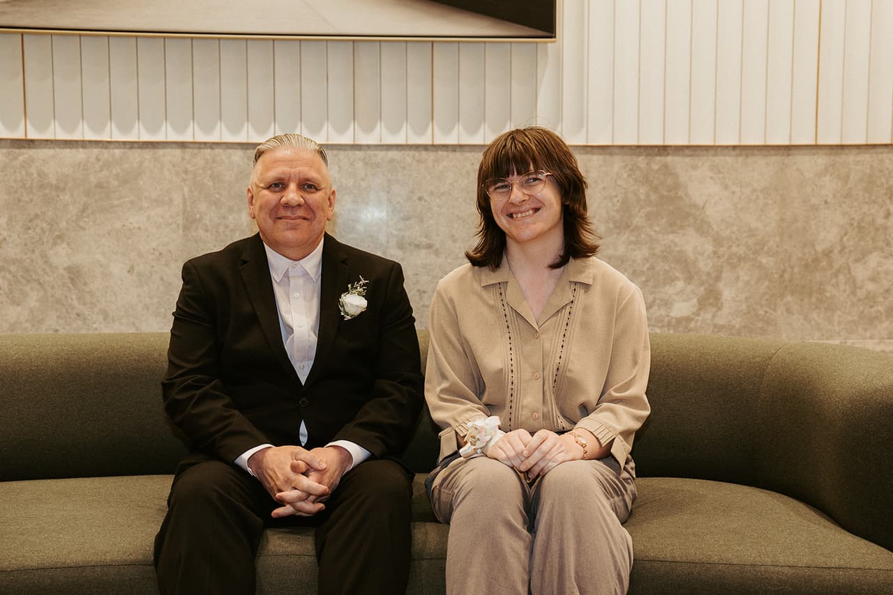 Jon and a guest sitting on the green sofa in the registry foyer for a family photo