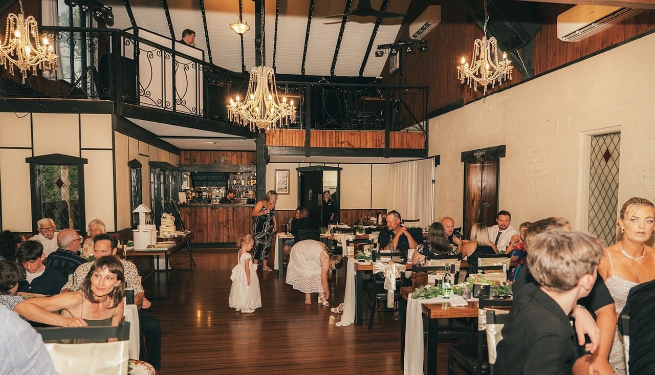 The reception hall in the evening, guests dancing on the timber floor beside the tables