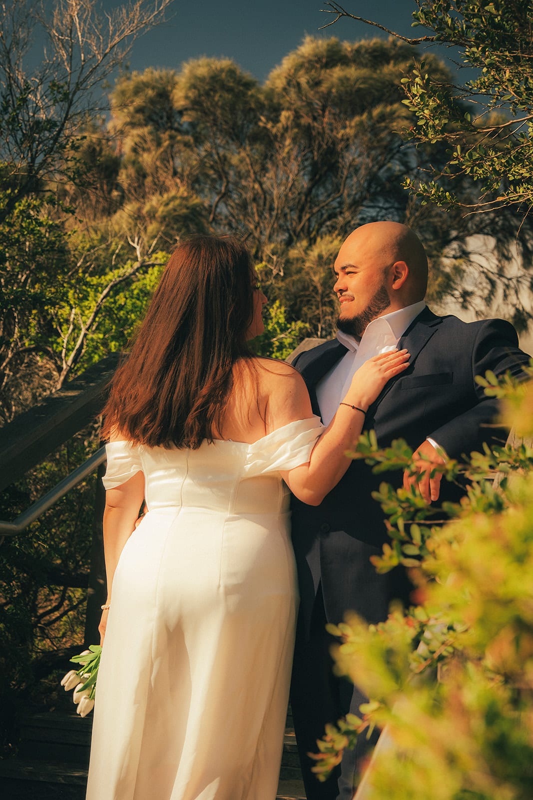 Martina and Diego among the green coastal scrub beside the timber steps behind the beach