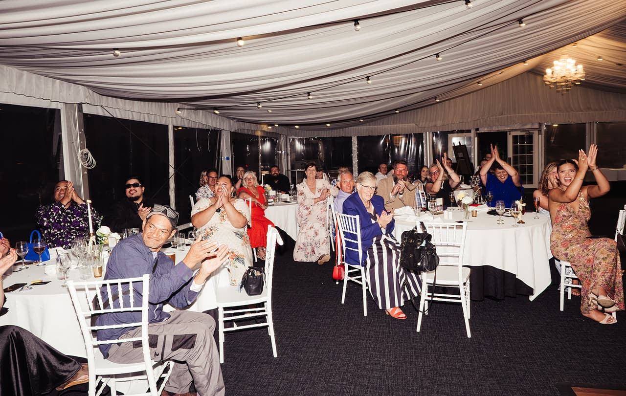 Guests applauding at their tables in the marquee after dark