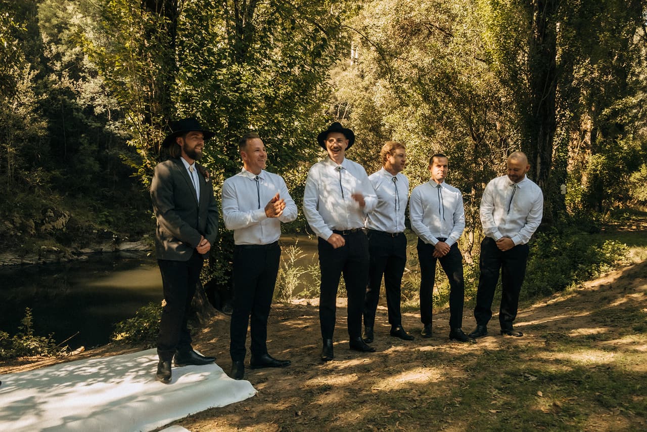 Todd and his groomsmen waiting on the grass beside the river before the ceremony