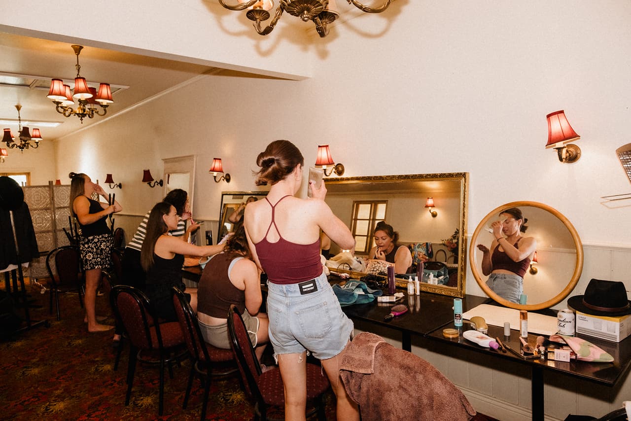 The room where the women got ready, with chandeliers, red patterned carpet and a long table of mirrors for hair and makeup