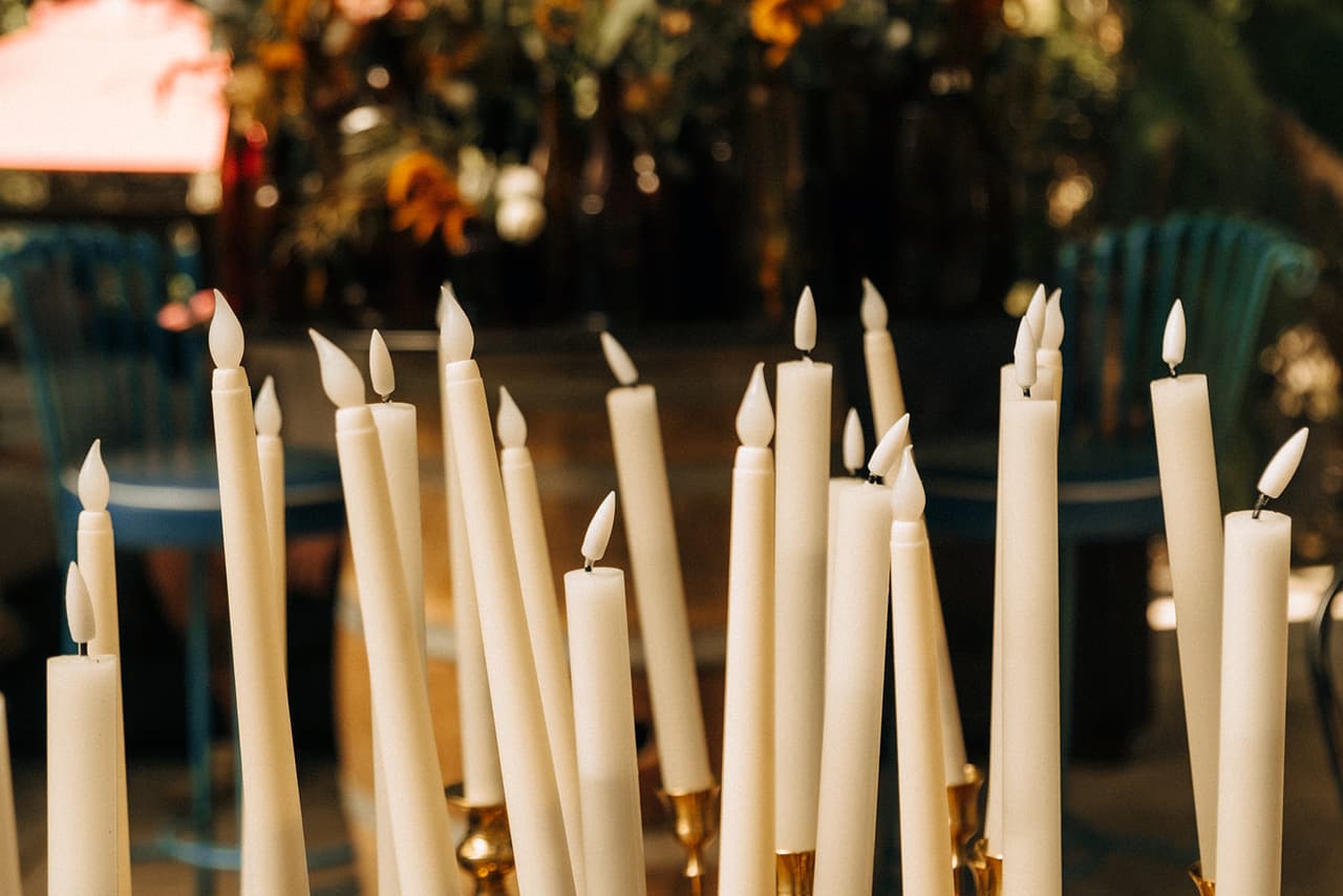 Tall white taper candles glowing in brass holders