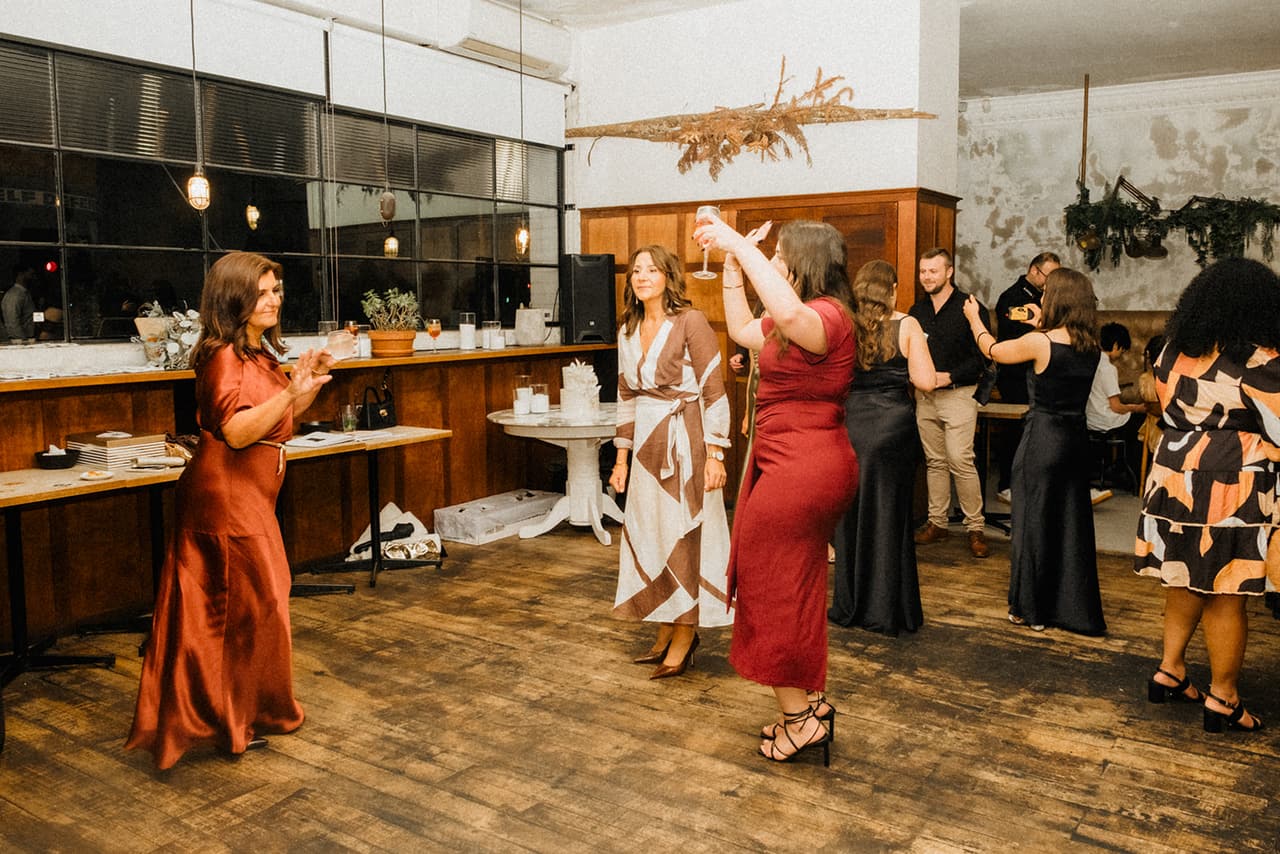 Guests dancing on the floorboards under a hanging installation of dried flowers