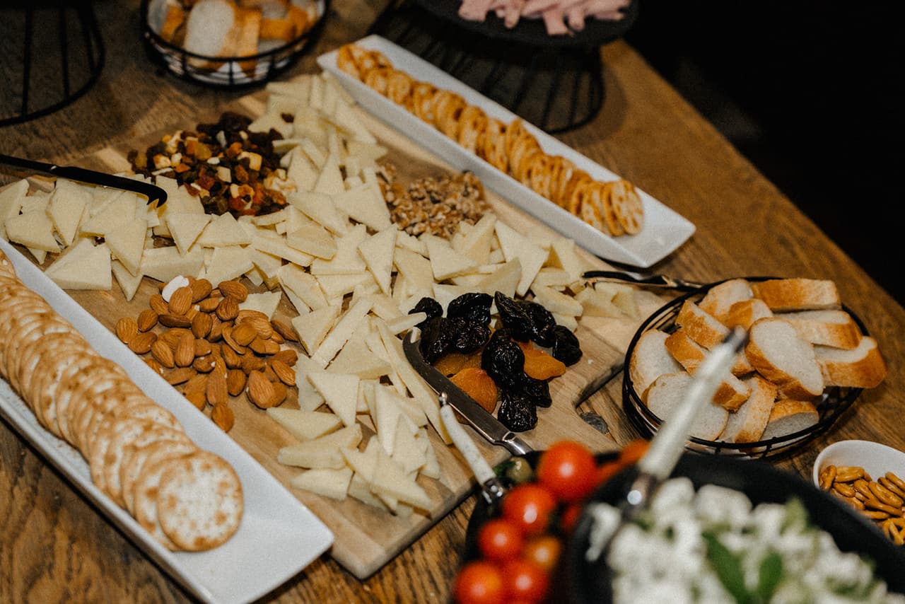 Cheese, crackers, almonds, dried fruit and bread laid out on the grazing table