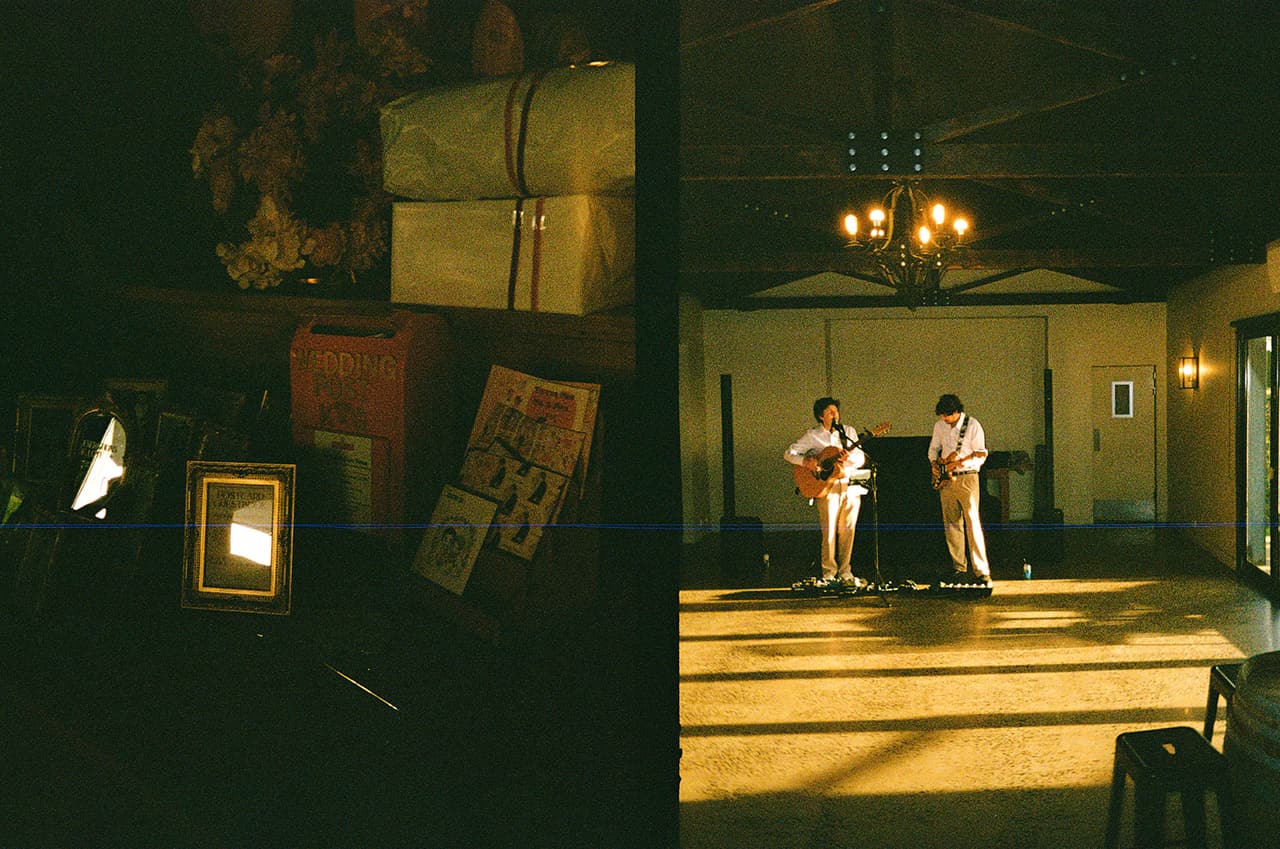 Two half frames side by side: a corner of the reception with gold frames and a vintage suitcase, and the duo playing on the open floor in the evening light, on 35mm film