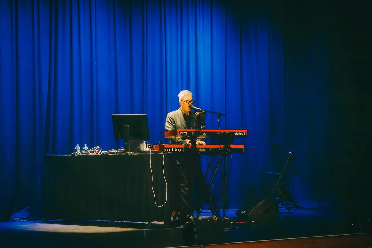 A musician at a keyboard on the stage in blue light