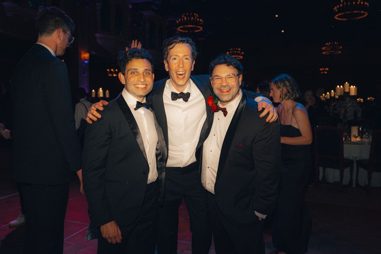 Three groomsmen in black tie laughing on the dance floor