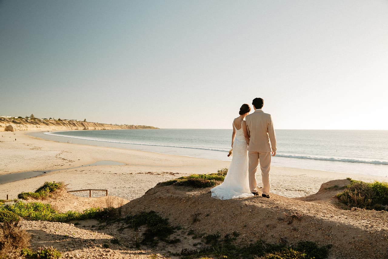 Sayuri and Shuto on the sandy point above the beach, looking along the long curve of sand and sea