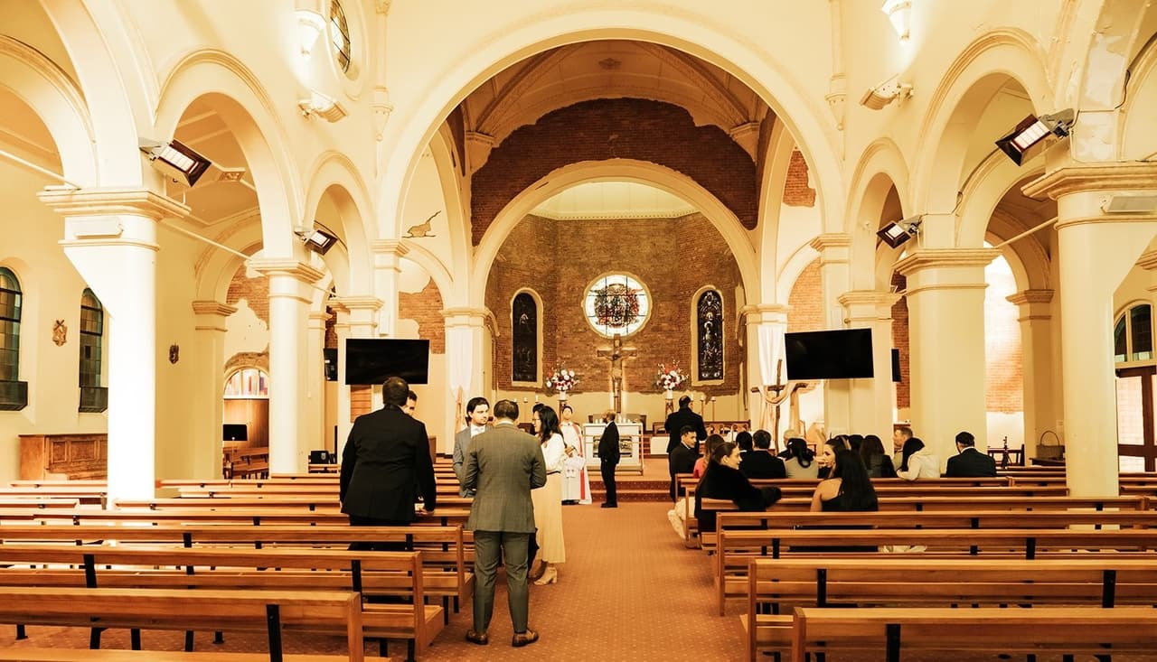 The long centre aisle and timber pews as guests arrive, the sanctuary at the far end
