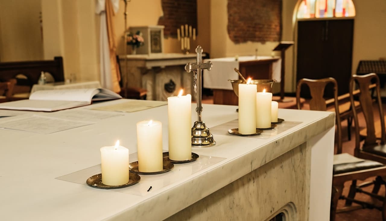 Candles and a small cross on the white marble altar