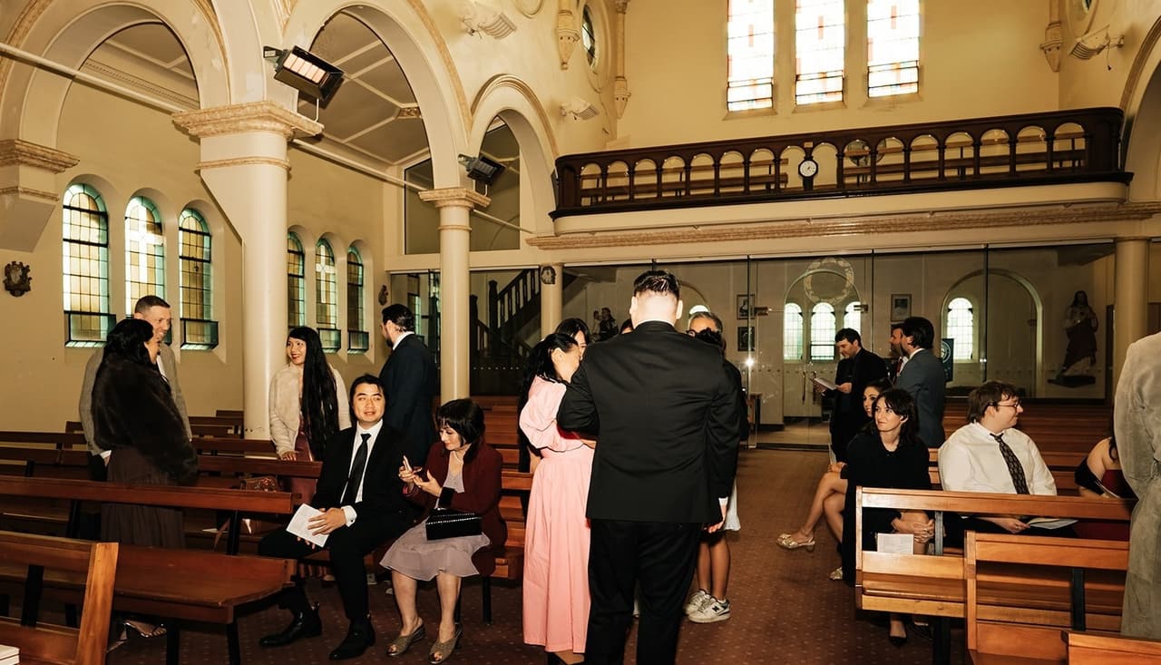 Guests arriving and finding their seats, the timber choir gallery at the back of the church