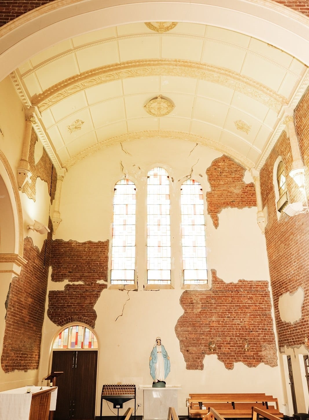 A side aisle with timber pews, a statue of Mary and tall windows above