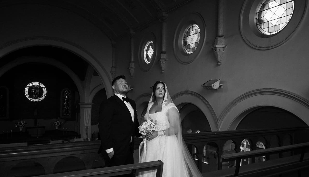 Black and white photo of the couple in the choir gallery, the nave and round windows behind them
