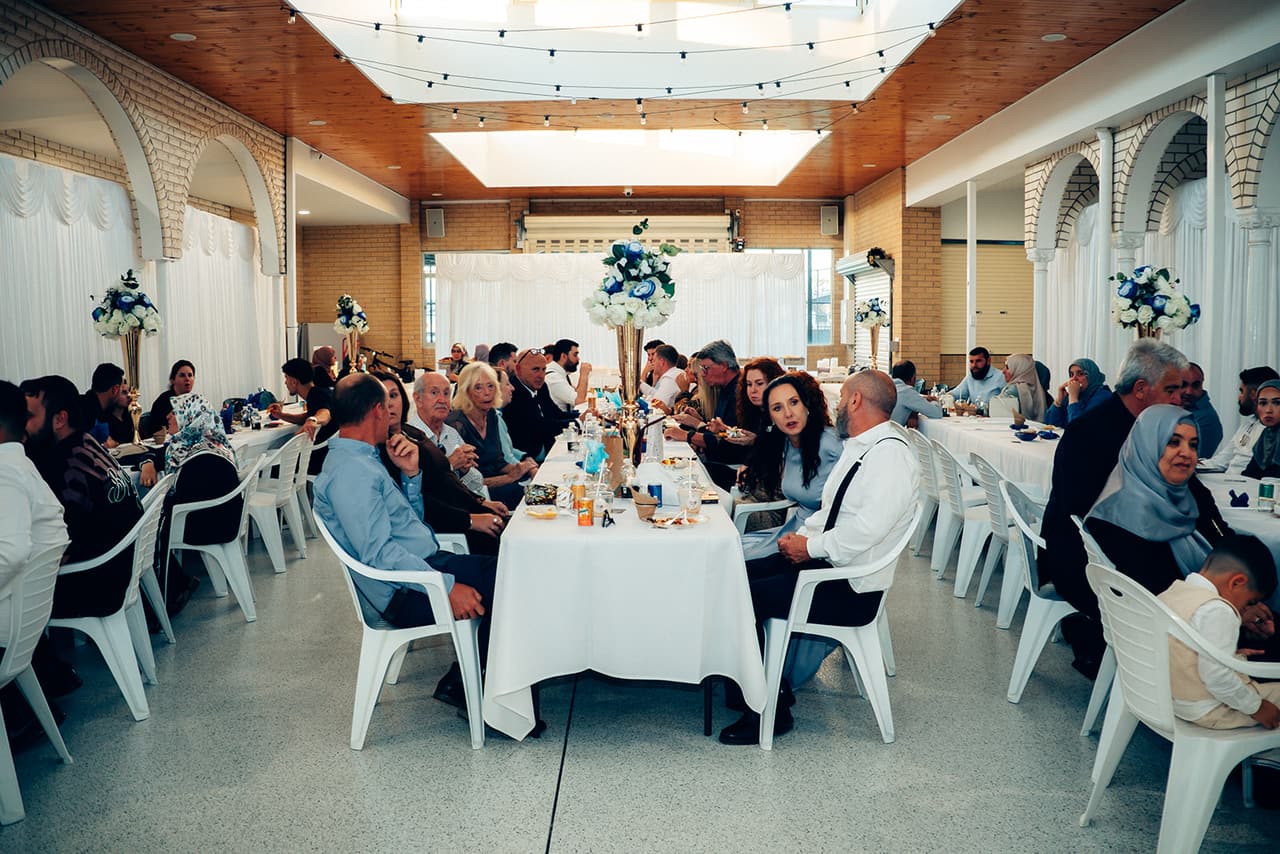 Guests at long white tables down the length of the hall during dinner, under the timber ceiling and skylights