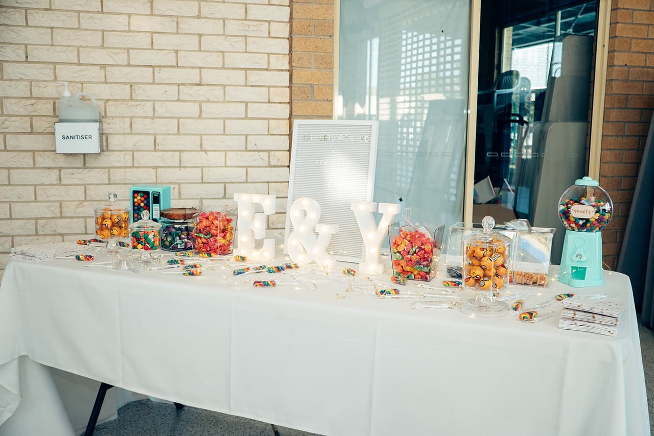 A lolly table with jars of sweets and light-up E and Y letters against a cream brick wall