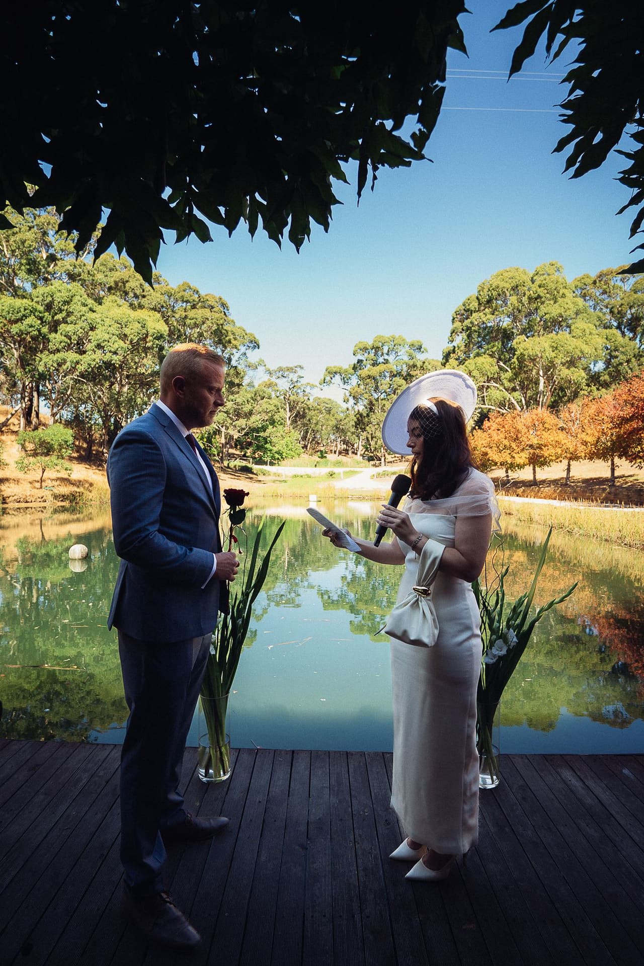 Kim and Ben on the Boatshed deck seen from inside, the pond stretching away to the autumn trees
