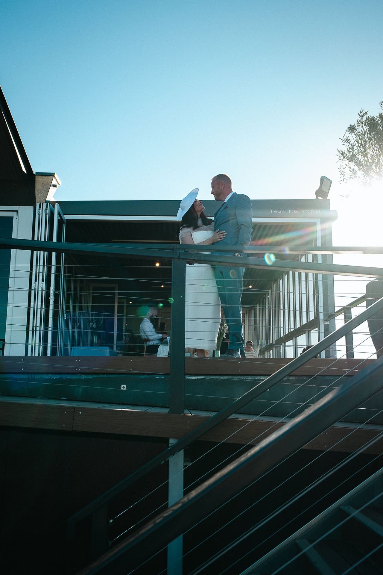 Kim and Ben on the deck of the restaurant above the stairs, the late sun behind them