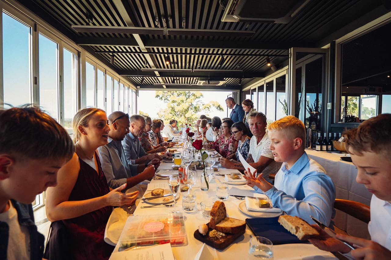 A long table running down the glass-walled restaurant, family and friends sitting down to dinner