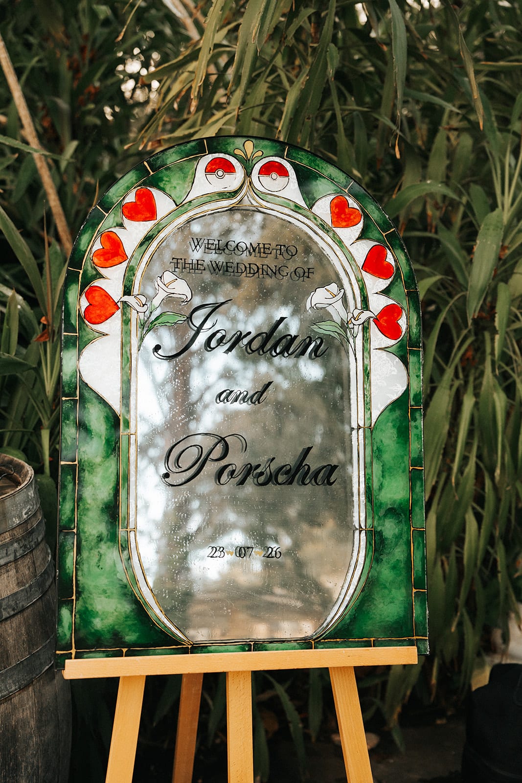 A mirrored welcome sign with Porscha and Jordan’s first names, framed in red roses, on a gold easel
