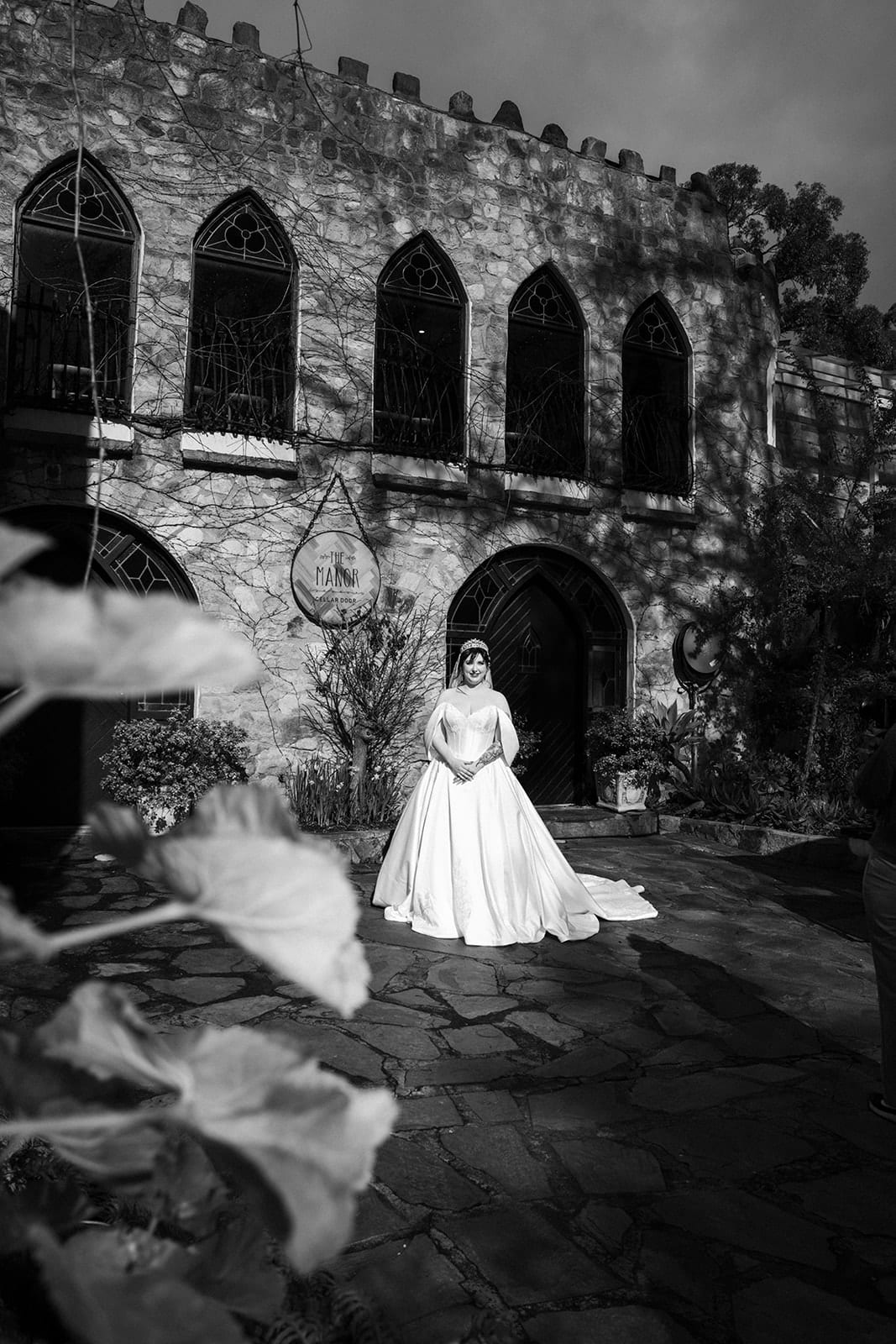 Black and white photo of Porscha on the lawn below the stone arches of the castle