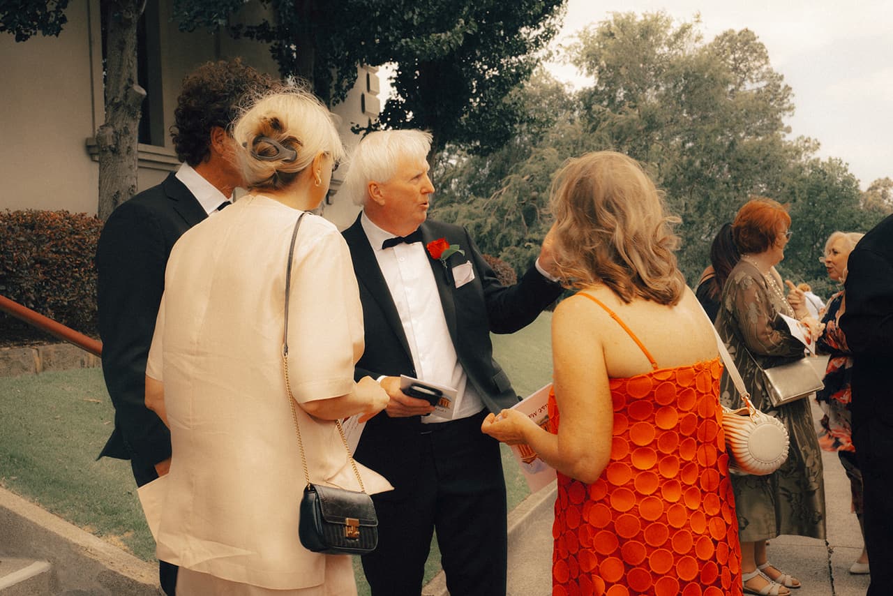 Guests catching up on the lawn beside the chapel after the ceremony