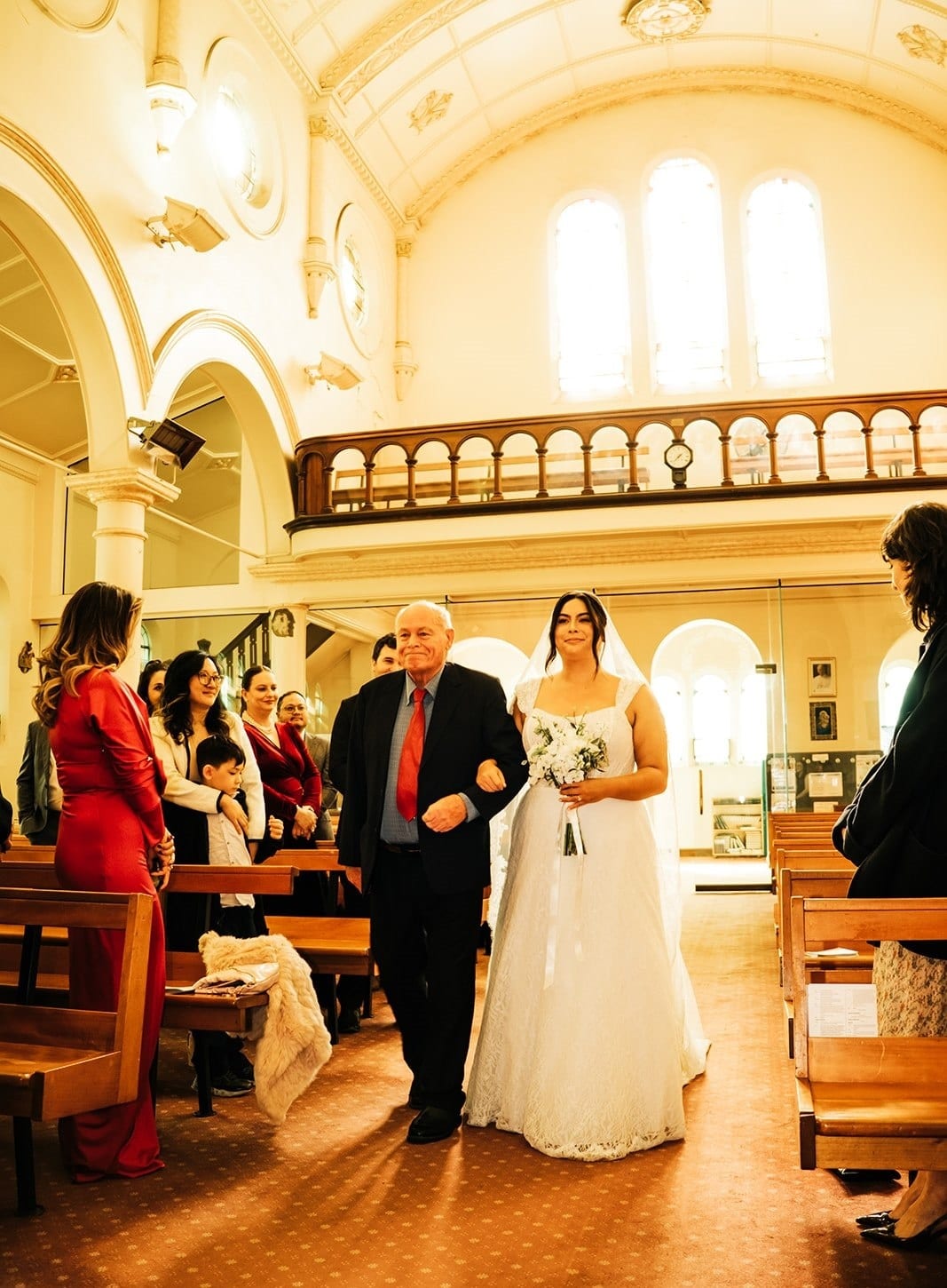 Ashley walking down the aisle on her dad’s arm as the guests stand
