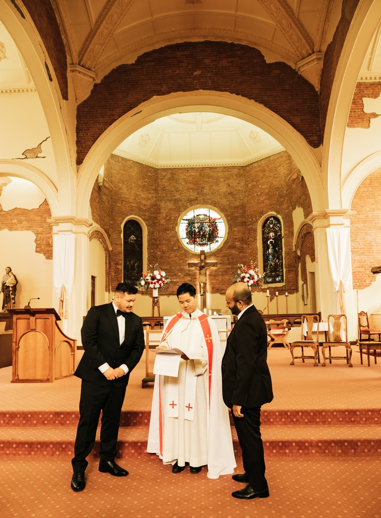 Bryan and his best man talking with the priest in front of the altar before the ceremony