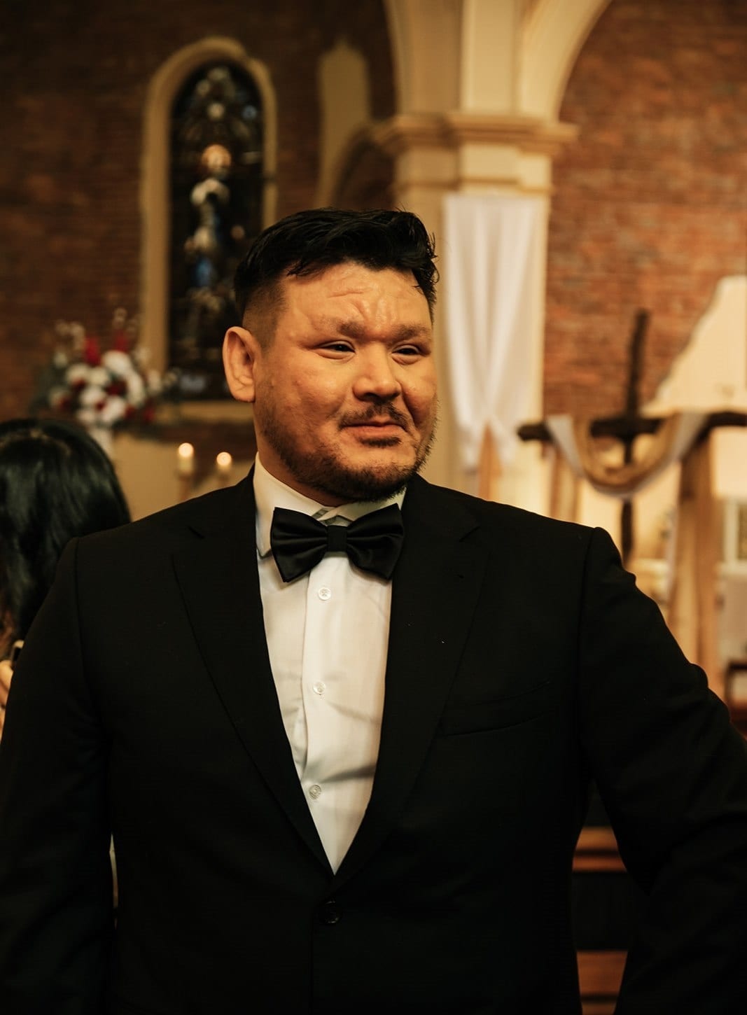 Bryan smiling as guests arrive, the round stained glass window behind him