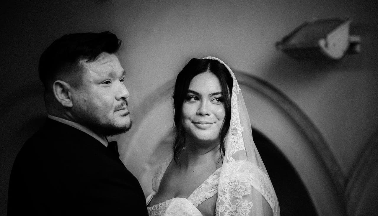 Black and white photo of Ashley smiling up at Bryan under the arches inside the church