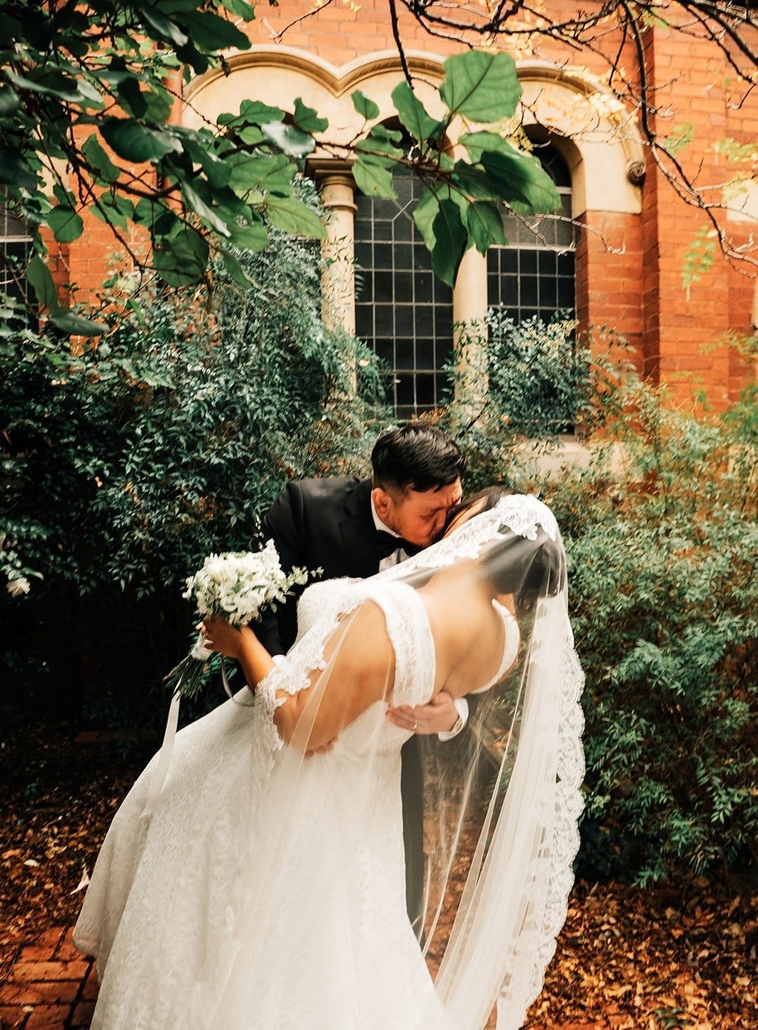 Bryan dipping Ashley for a kiss in the garden, her veil trailing