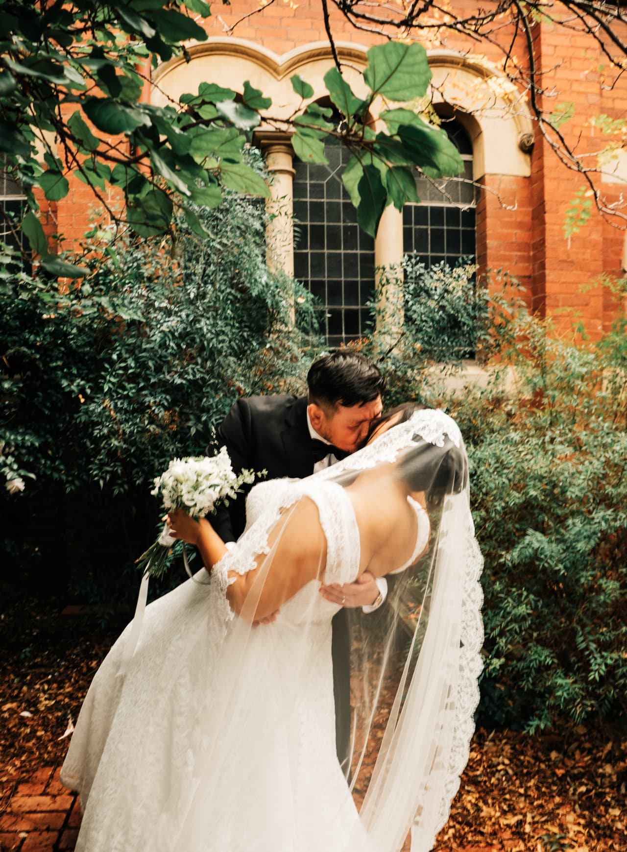 Bryan dipping Ashley for a kiss in the garden, her veil trailing