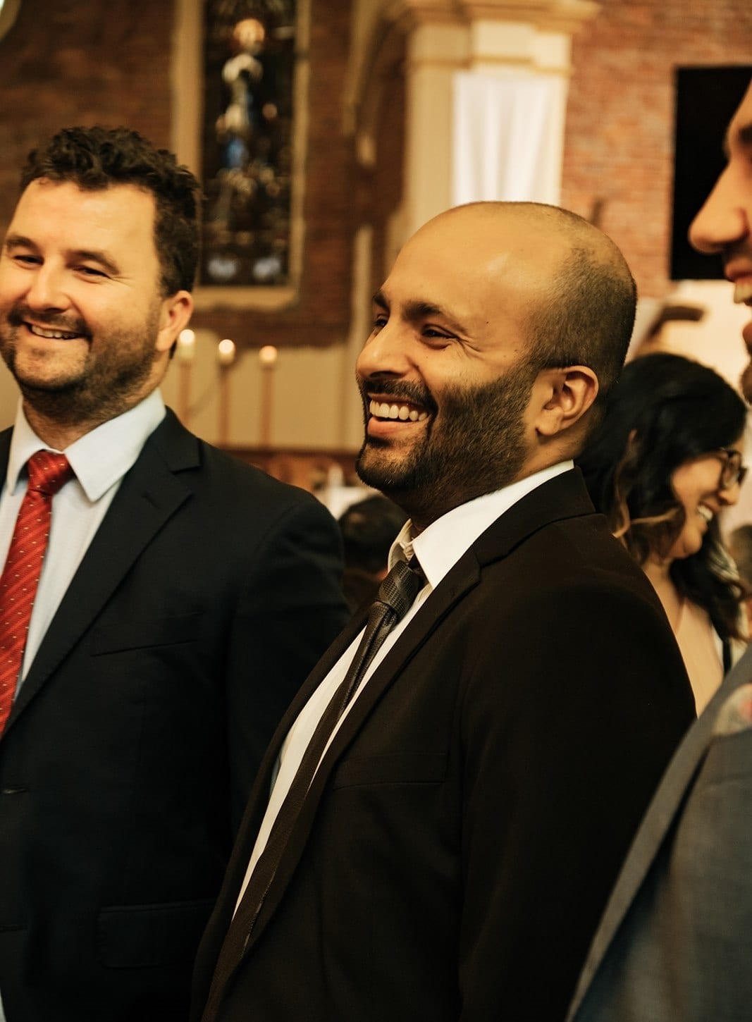 Two of the groomsmen laughing together near the front of the church