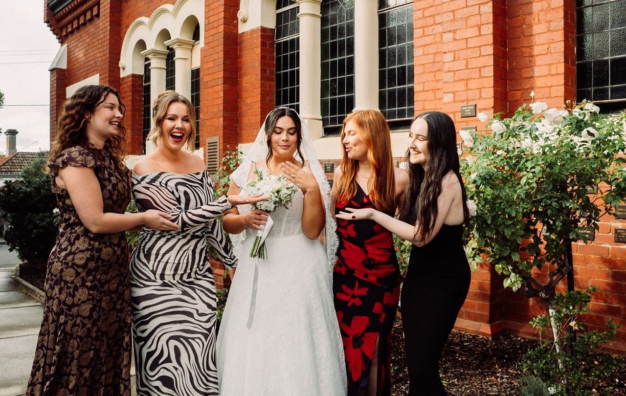 Ashley laughing with a hand to her face as four friends gather round her outside the church