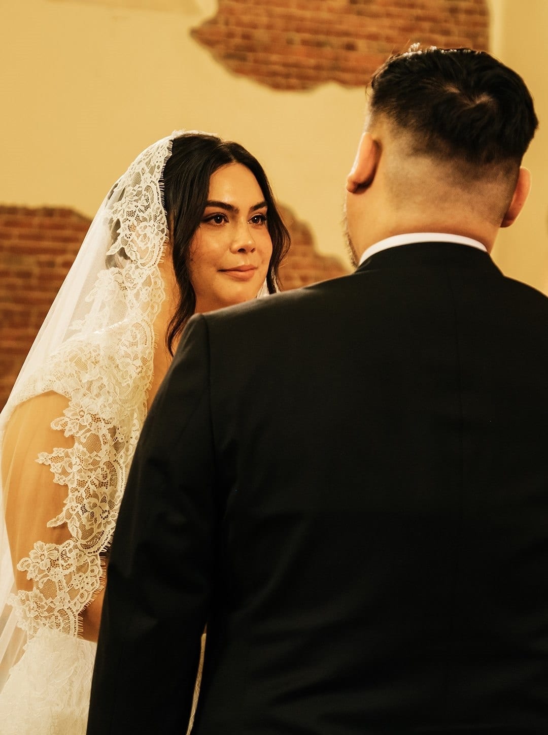 Ashley looking at Bryan over his shoulder as they face each other for their vows