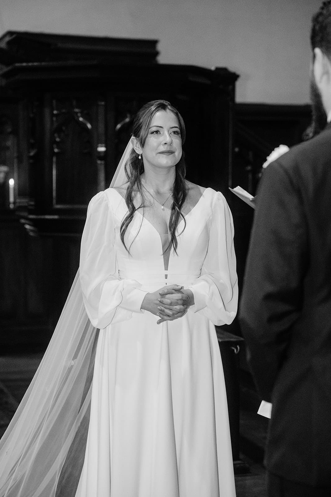 Black and white photo of Bianca smiling in her long veil at the front of the church