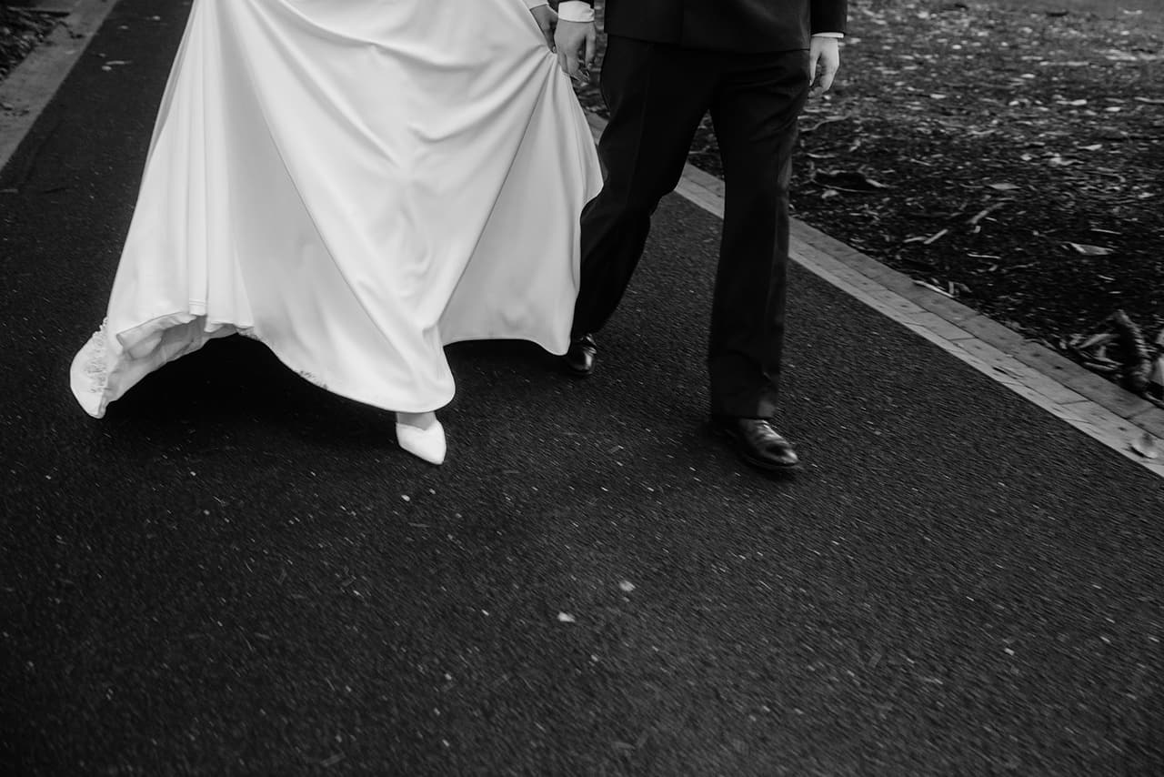 Black and white close up of Bianca’s dress swinging as she and Aidan walk along the garden path