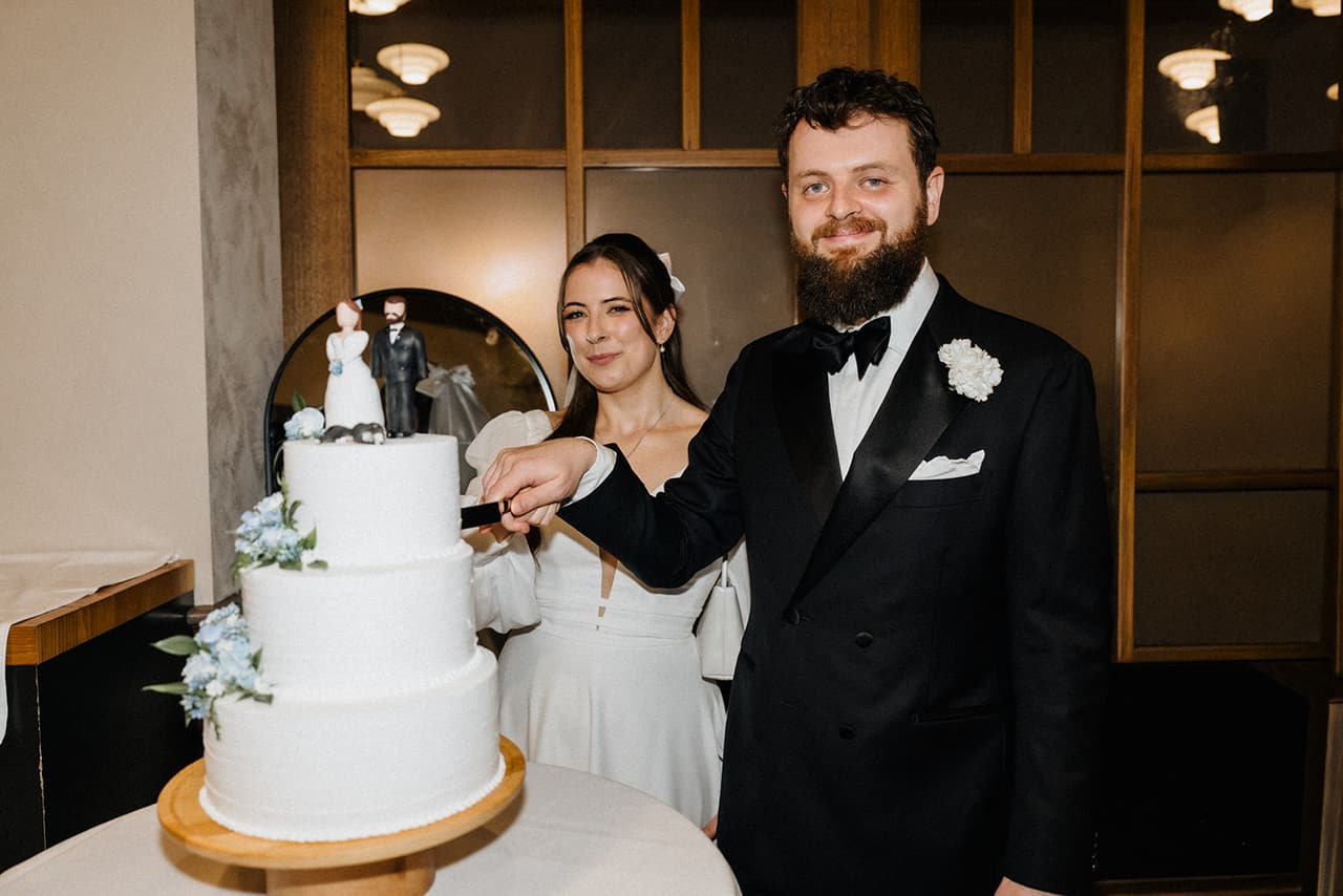 Bianca and Aidan cutting a tiered white cake at the reception