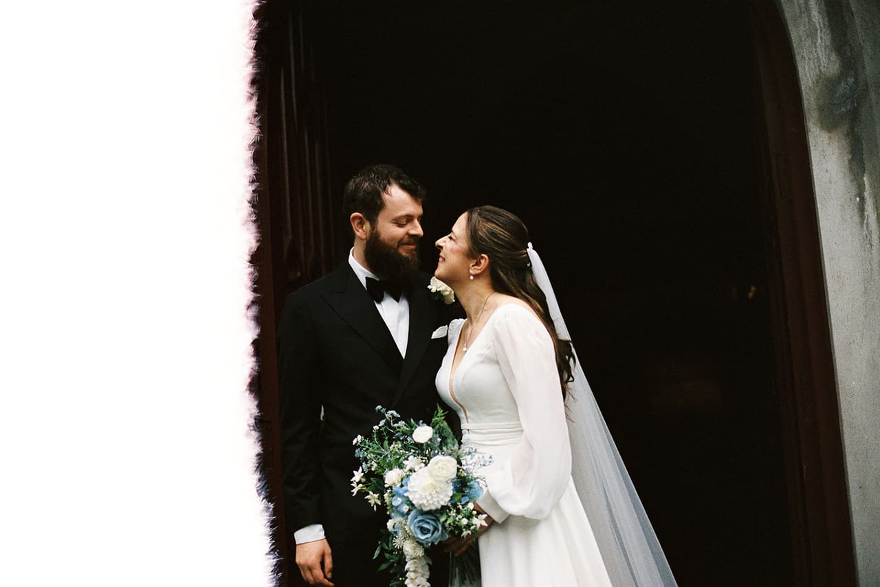 Aidan and Bianca close together in a dark doorway, the end of the roll burnt white beside them, on 35mm film