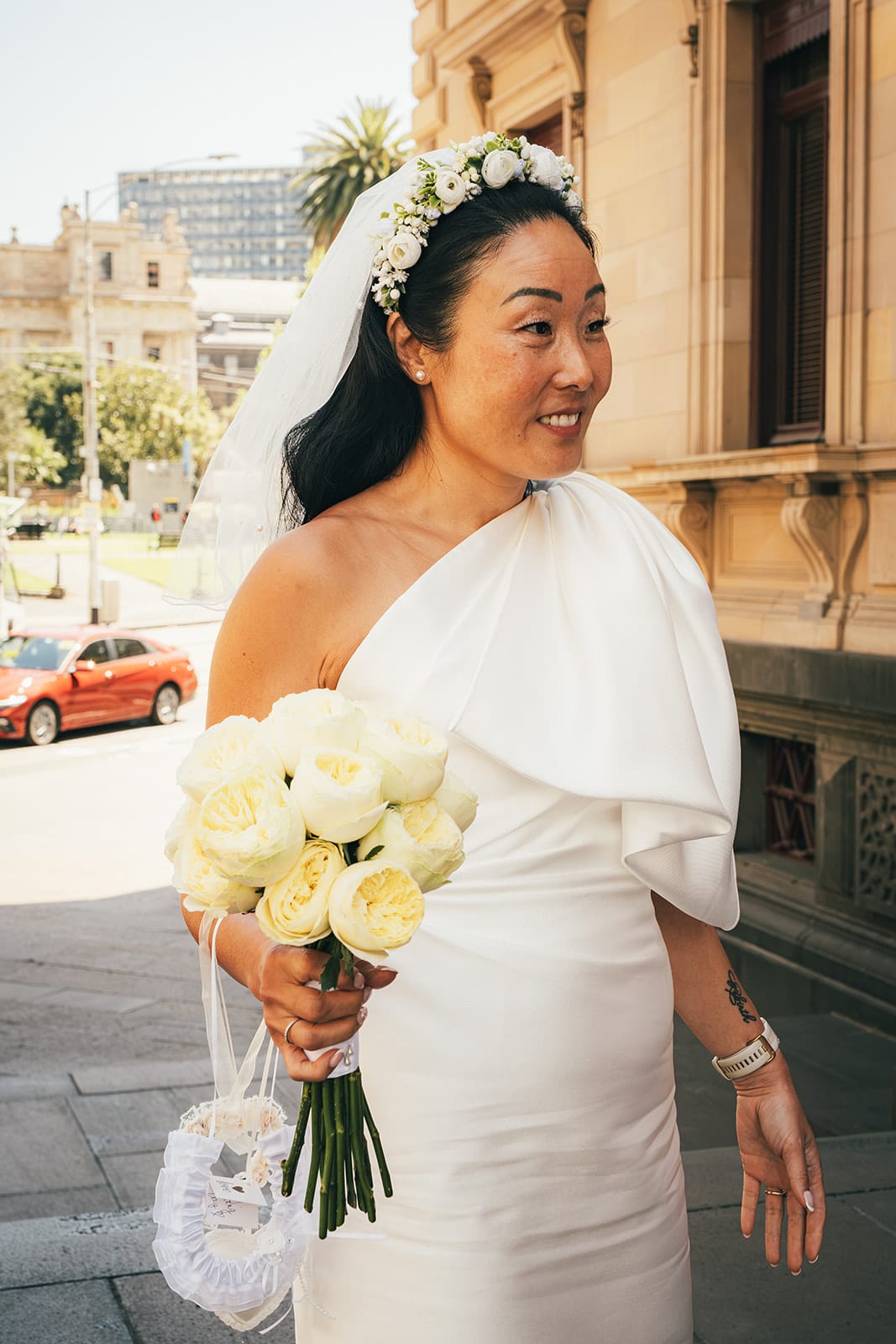 Cecile smiling outside the Old Treasury Building with her roses and the lace heart on her wrist