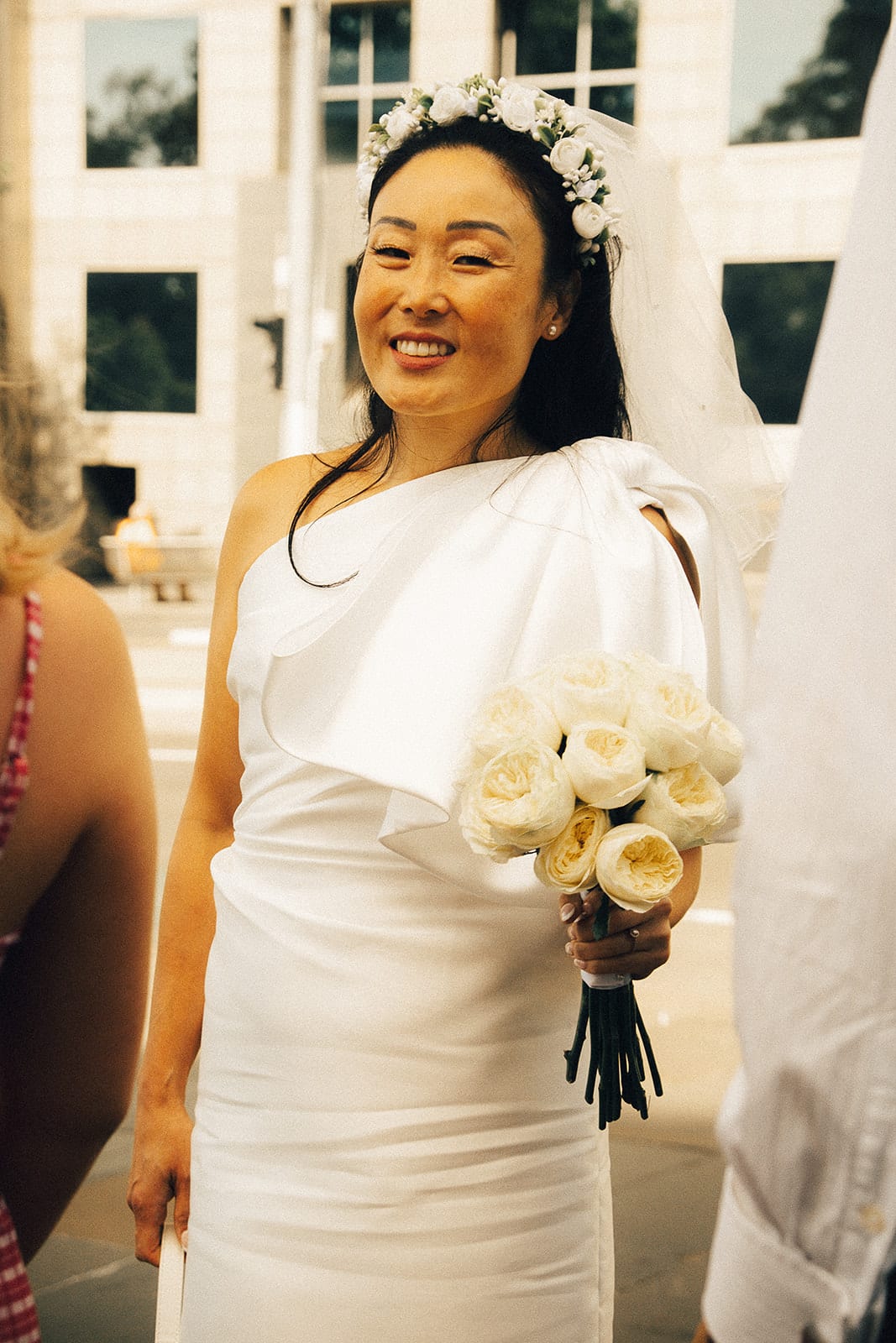 Cecile smiling in the sun with her pale yellow roses, a flower crown and a short veil