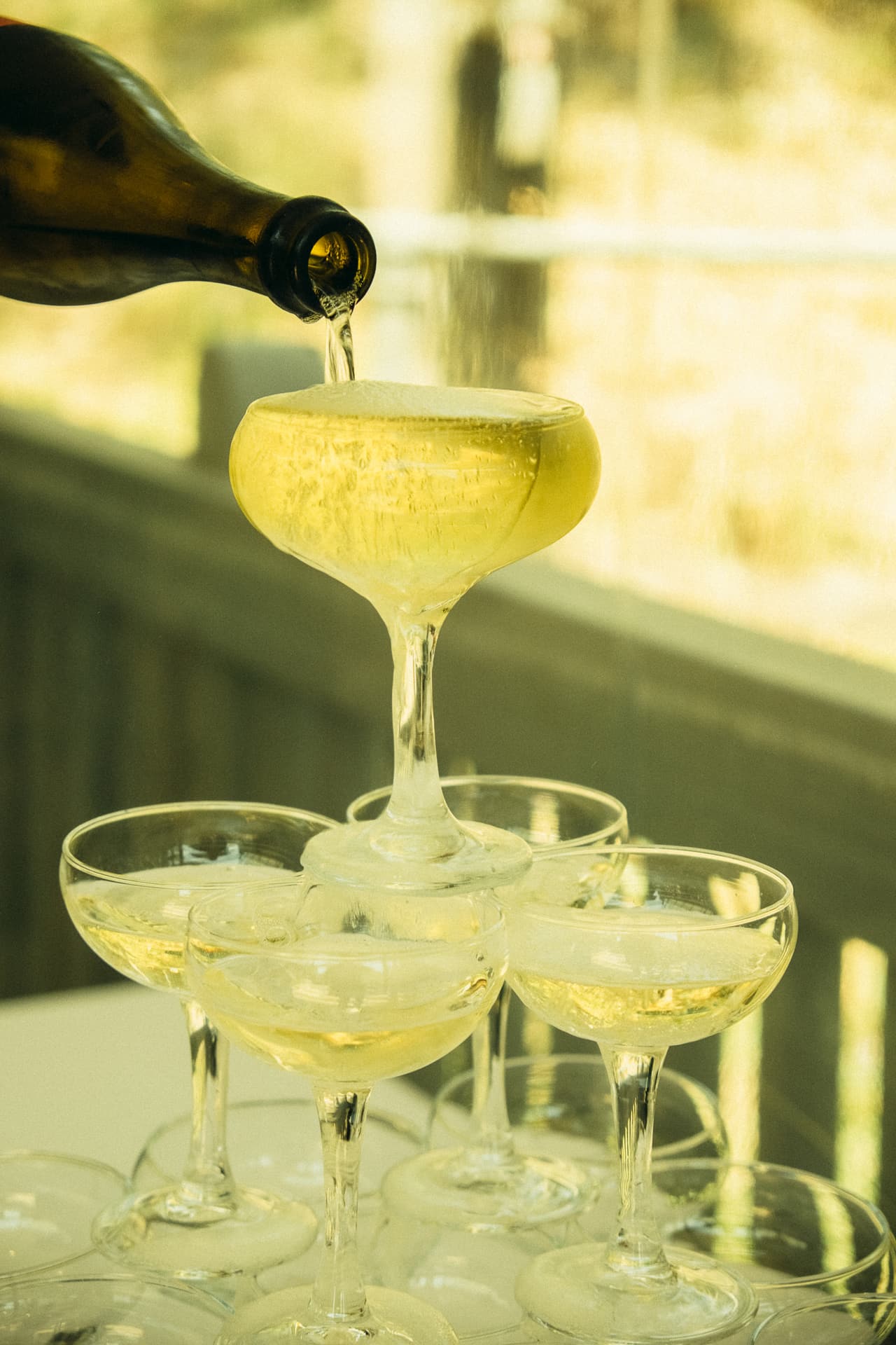 Champagne being poured into a tower of coupe glasses at the boathouse