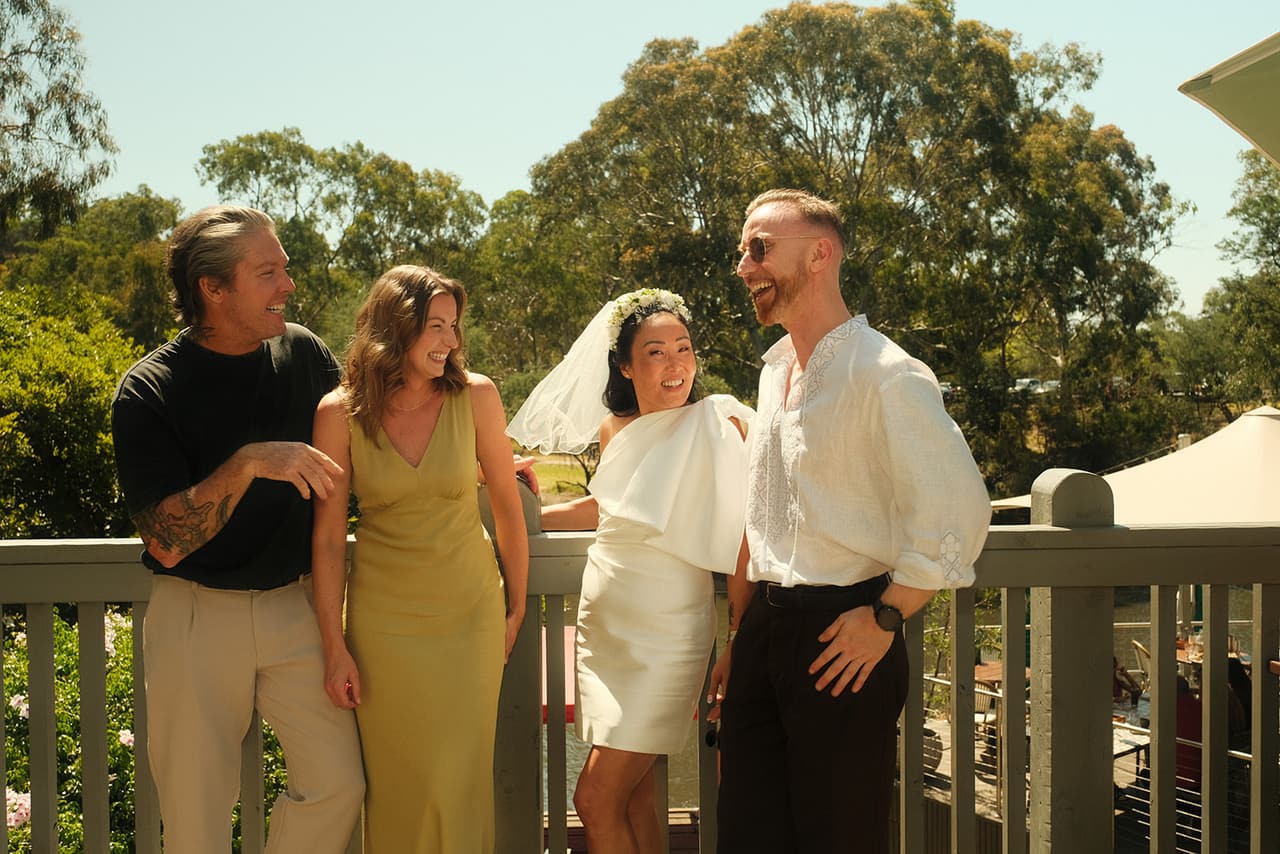 Cecile and Stefan laughing with friends on a timber deck by the river