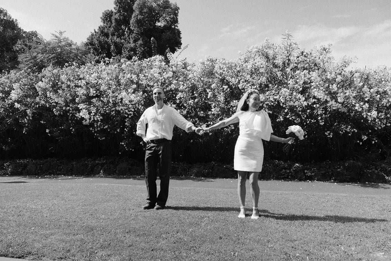 Black and white photo of Cecile and Stefan reaching for each other across a lawn